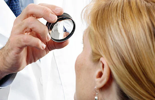 Oftalmologista examinando o fundo do olho de uma paciente com lente de mapeamento de retina
